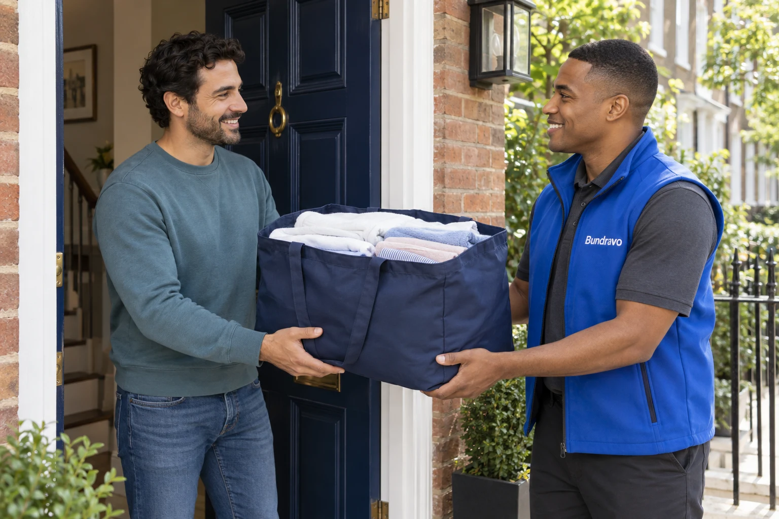 A Bundravo driver returning clean, folded laundry to a customer at his door.